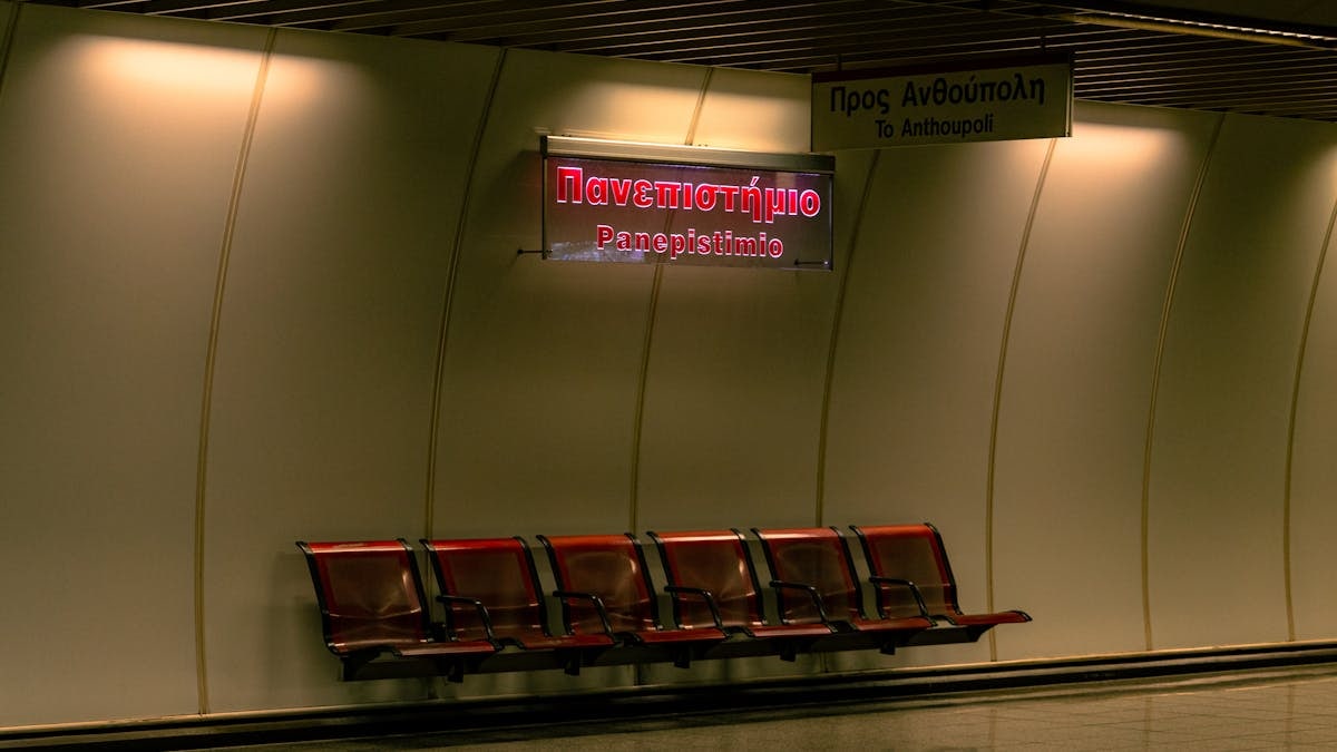 Empty Athens metro station with benches and signage at night, creating a quiet urban ambiance.
